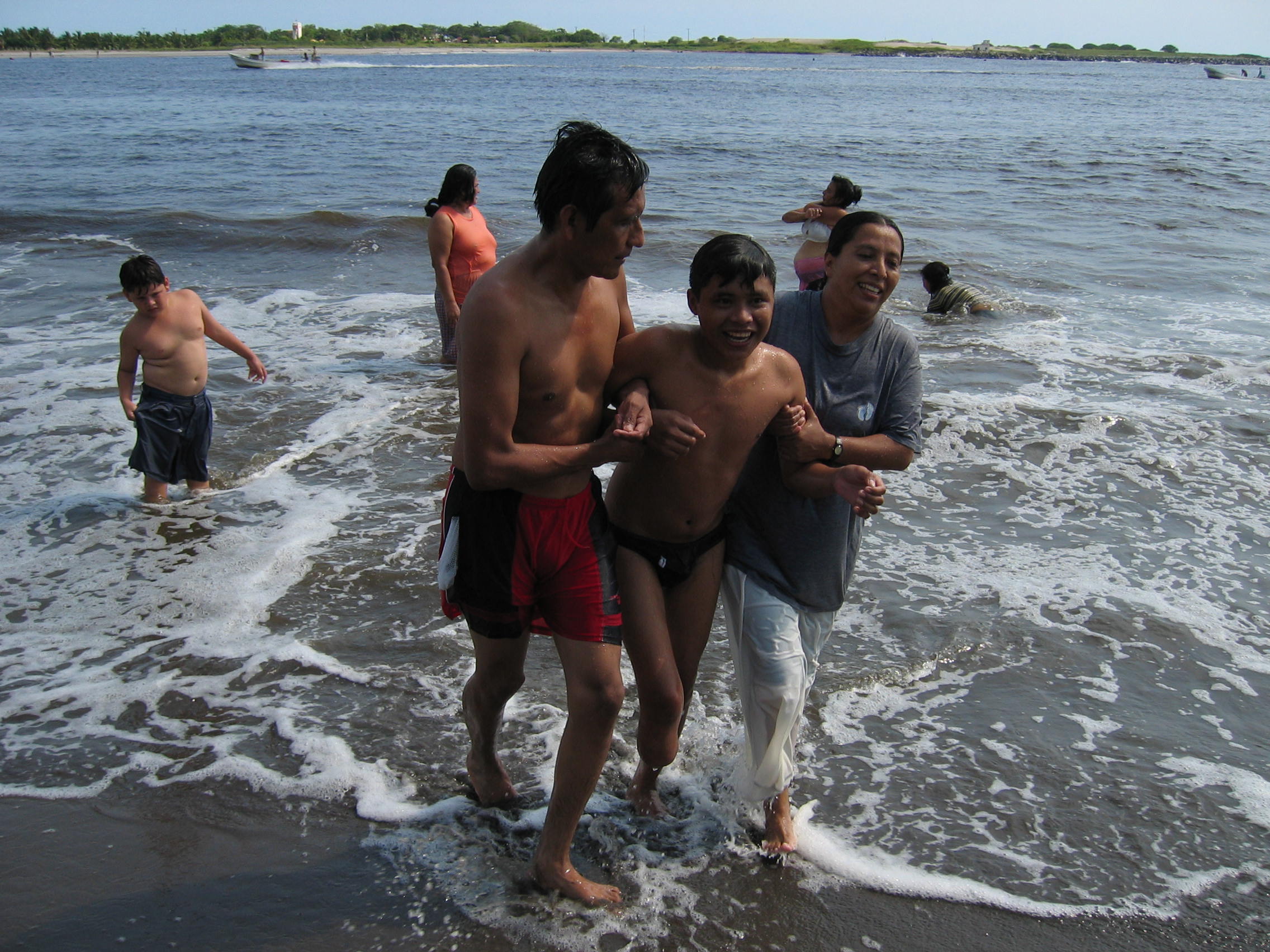 Olga Sánchez Martínez and a shelter volunteer help Hugo Tambrís Sióp, 14, get out of the ocean.
